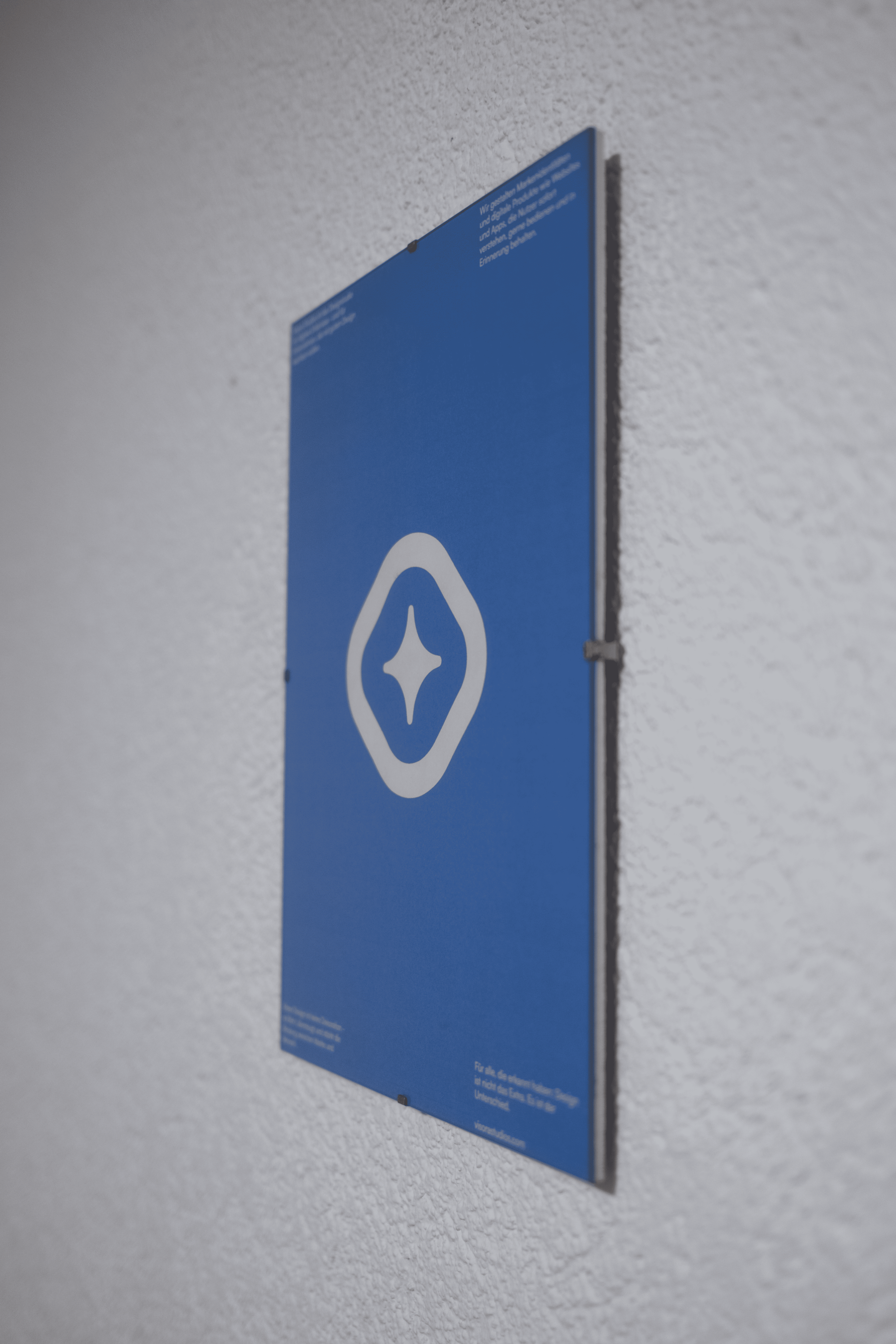Visora-Logo auf einem blauen Poster, das an einer weißen, strukturierten Wand hängt